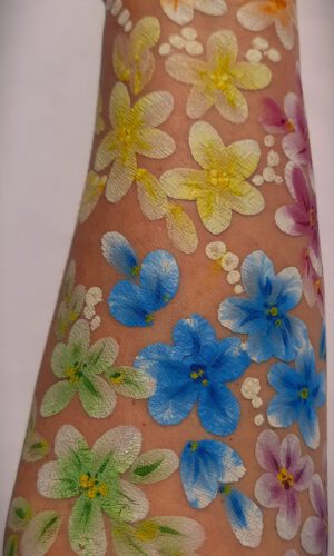 Arm mit bunten, aufgemalten Blumen in verschiedenen Farben und kleinen weißen Punkten dazwischen