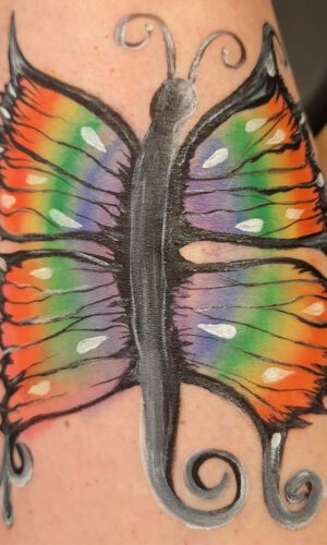 Bunter Schmetterling mit geschwungenen Antennen und Flügelenden auf Haut gemalt