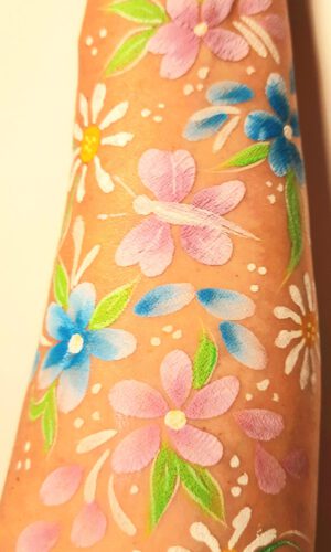 Unterarm mit bunten Blumen- und Blättermalereien in Pastellfarben